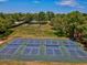 Multiple tennis courts with green and blue surfacing are ready for play, surrounded by mature trees and landscaping at 10187 Holly Berry Dr, Weeki Wachee, FL 34613