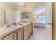 Bright bathroom with double vanity, wood cabinetry, and an open doorway leading to a bedroom at 1032 Walnut Hill Ct, Spring Hill, FL 34609