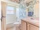 Cozy bathroom features patterned wallpaper, shower-tub combo, and vanity at 1032 Walnut Hill Ct, Spring Hill, FL 34609