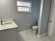 Bathroom features white marble floors, gray walls, toilet, white sink cabinet, and window for natural light at 10906 Carnelian Ln, Riverview, FL 33578