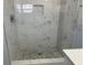 Shower featuring white marble tiles, gray pebble flooring, and built in storage at 10906 Carnelian Ln, Riverview, FL 33578