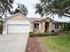 Charming home with a two-car garage, manicured landscaping, and a welcoming red front door at 1121 Riveredge Dr, Tarpon Springs, FL 34689