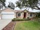 Charming single-story home featuring a well-manicured lawn, red front door, and attached two-car garage at 1121 Riveredge Dr, Tarpon Springs, FL 34689