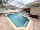 Private screened-in pool with blue tile accents and brick patio area, complemented by a hot tub at 1121 Riveredge Dr, Tarpon Springs, FL 34689