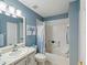 Bright bathroom features blue accents, tub with shower, and white cabinets at 11342 Hollander Ave, Hudson, FL 34667