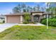 Inviting single-story home with a two-car garage, manicured landscaping, and an arched entryway at 11443 Marsh Creek Ct, New Port Richey, FL 34654