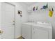 Bright laundry room with washer, dryer, shelving and door to the garage at 11443 Marsh Creek Ct, New Port Richey, FL 34654