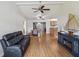 Open-concept living room with wood floors, a ceiling fan, and a comfortable black leather sofa at 11512 Yellow Birch Ct, New Port Richey, FL 34654