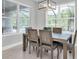 Dining room with a wood table and chairs lit by a modern chandelier and views of the pool outside at 12539 Wetmore Ct, Odessa, FL 33556