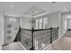 Open hallway with a modern chandelier, staircase with decorative iron railings and light gray walls at 12539 Wetmore Ct, Odessa, FL 33556
