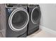 Modern laundry room featuring side-by-side washer and dryer in a neutral color scheme at 12539 Wetmore Ct, Odessa, FL 33556