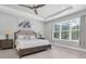 Well-lit primary bedroom featuring a ceiling fan, bench, and large windows with a view of the backyard at 12539 Wetmore Ct, Odessa, FL 33556