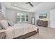 A well-lit primary bedroom includes a ceiling fan, large windows and a dresser with a mirror and television at 12539 Wetmore Ct, Odessa, FL 33556