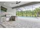 Outdoor kitchen featuring stone countertops, a stainless steel grill, and views of the pool and greenery at 12539 Wetmore Ct, Odessa, FL 33556