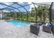 View of the screened-in pool area with comfortable lounge seating and verdant surroundings at 12539 Wetmore Ct, Odessa, FL 33556
