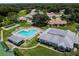 An aerial view of the community pool, clubhouse, and surrounding homes with lush landscaping and trees at 13039 Topflite Ct, Hudson, FL 34669