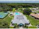 Aerial view highlighting community amenities, tennis courts, swimming pool, and community center with mature trees at 13039 Topflite Ct, Hudson, FL 34669