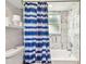 Bathtub with stylish tile and blue patterned shower curtain with plenty of storage for toiletries at 13039 Topflite Ct, Hudson, FL 34669