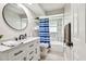 Modern bathroom featuring a round mirror, sleek vanity, and a bathtub with stylish tile at 13039 Topflite Ct, Hudson, FL 34669