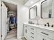 Bathroom featuring a double vanity with framed mirrors, open closet, and modern fixtures at 13039 Topflite Ct, Hudson, FL 34669