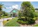 Inviting clubhouse featuring lush, colorful landscaping, a well-maintained lawn, and a charming entrance with green awnings at 13039 Topflite Ct, Hudson, FL 34669