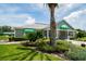 Inviting clubhouse exterior featuring a well-manicured lawn, lush landscaping, and a charming entrance with green awnings at 13039 Topflite Ct, Hudson, FL 34669