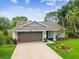 Well-maintained single-story home featuring a lush lawn, mature trees, and a convenient two-car garage at 13039 Topflite Ct, Hudson, FL 34669