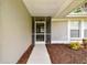 Covered front porch with door and full view of the storm door and landscape at 13039 Topflite Ct, Hudson, FL 34669