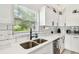 Modern kitchen with stainless steel sink, white cabinets, subway tile, and a view to the backyard at 13039 Topflite Ct, Hudson, FL 34669