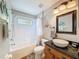 Bathroom with a white tub-shower combination, a light wood vanity with granite top and a decorative mirror at 13850 Royston Bnd, Hudson, FL 34669