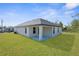 Back of house featuring a covered patio, lush green grass, and white exterior at 14042 Amero Ln, Spring Hill, FL 34609