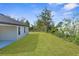 Spacious backyard featuring green grass, and a partial view of the house with blue trim at 14042 Amero Ln, Spring Hill, FL 34609