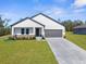 Charming single-story home showcases a modern exterior, a well-manicured lawn, and an attached two-car garage at 14042 Amero Ln, Spring Hill, FL 34609