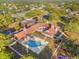 Aerial view shows a red-roofed building with a blue swimming pool and playground surrounded by trees at 14163 Andrew Scott Rd, Spring Hill, FL 34609