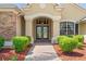 Elegant front entrance with decorative glass doors, sidelights, and manicured shrubs at 14163 Andrew Scott Rd, Spring Hill, FL 34609