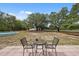 Enjoy outdoor relaxation on the patio with a table and chairs overlooking the lush backyard and pool at 14740 Loma Ave, Spring Hill, FL 34610
