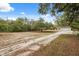 Long driveway leading to a house surrounded by mature trees and open spaces at 14740 Loma Ave, Spring Hill, FL 34610