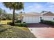Charming home featuring a well-manicured lawn and a red brick driveway leading to a two-car garage at 15038 Sterling Run, Brooksville, FL 34609