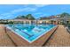 A shimmering swimming pool with a brick-paved deck is surrounded by lounge chairs and tables at 15038 Sterling Run, Brooksville, FL 34609