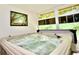 Close-up of a bubbling hot tub inside a sunroom, surrounded by windows at 1723 Cortleigh Dr, Trinity, FL 34655
