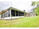 Exterior view of a home with a large sunroom featuring screened windows and a view of the landscaped yard at 1723 Cortleigh Dr, Trinity, FL 34655