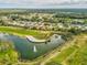 An aerial view of a golf course with a pond, sand trap, golf cart, and trees at 18418 Bent Pine Dr, Hudson, FL 34667