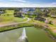 An aerial view of a golf course, pond with a fountain, and trees at 18418 Bent Pine Dr, Hudson, FL 34667