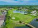 Aerial view of community featuring a golf course, lake, bridge, and residential homes amid lush landscaping at 18418 Bent Pine Dr, Hudson, FL 34667