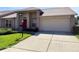 Inviting single-story home featuring a red front door, two-car garage, and well-maintained front yard at 18418 Bent Pine Dr, Hudson, FL 34667