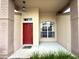 Close-up of the entryway with a vibrant red door and elegant architectural details in a neutral color palette at 18418 Bent Pine Dr, Hudson, FL 34667