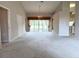 A spacious living room with carpet floors leads to the backyard through glass sliding doors and features an ornate chandelier at 18418 Bent Pine Dr, Hudson, FL 34667