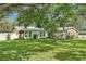 Attractive single-story home featuring a stone facade and a well-manicured lawn with mature trees at 18633 Oak Way Dr, Hudson, FL 34667