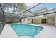An in-ground screened pool with a covered lanai and view of the house at 18633 Oak Way Dr, Hudson, FL 34667