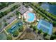 Aerial view of the community featuring a pool, tennis courts, playground, clubhouse, and surrounding greenery at 19082 Umberland Pl, Land O Lakes, FL 34638